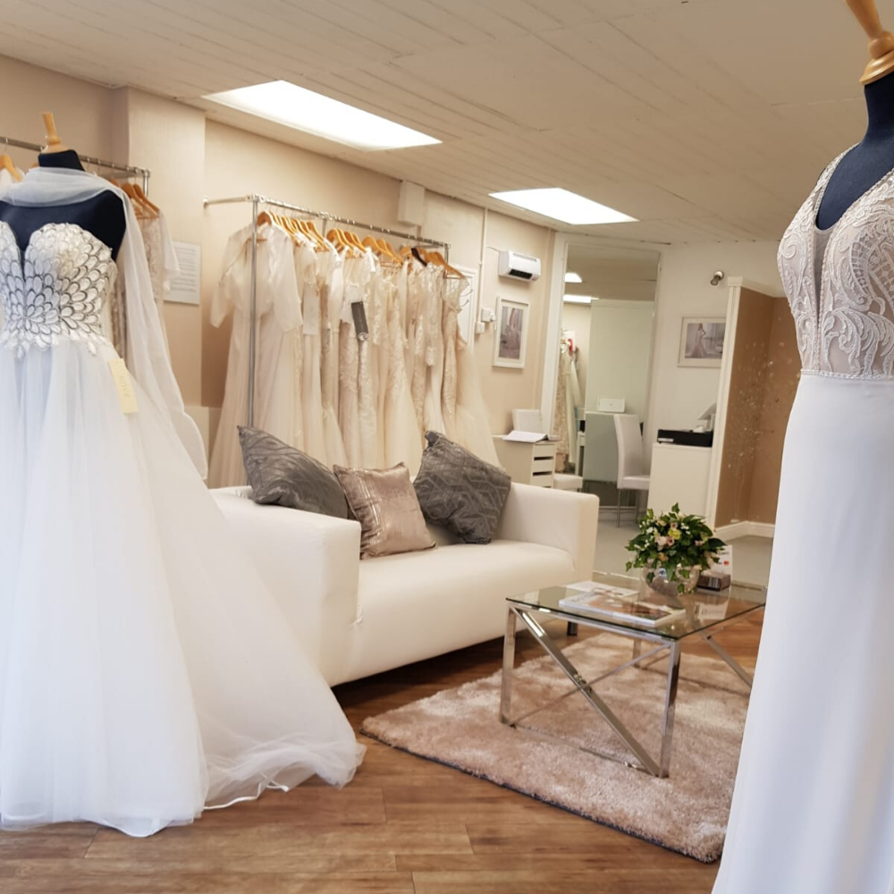 A light and spacious waiting room with two mannequins, a cream sofa and a rail of wedding dresses at Simply Wed Bridal in Newcastle 